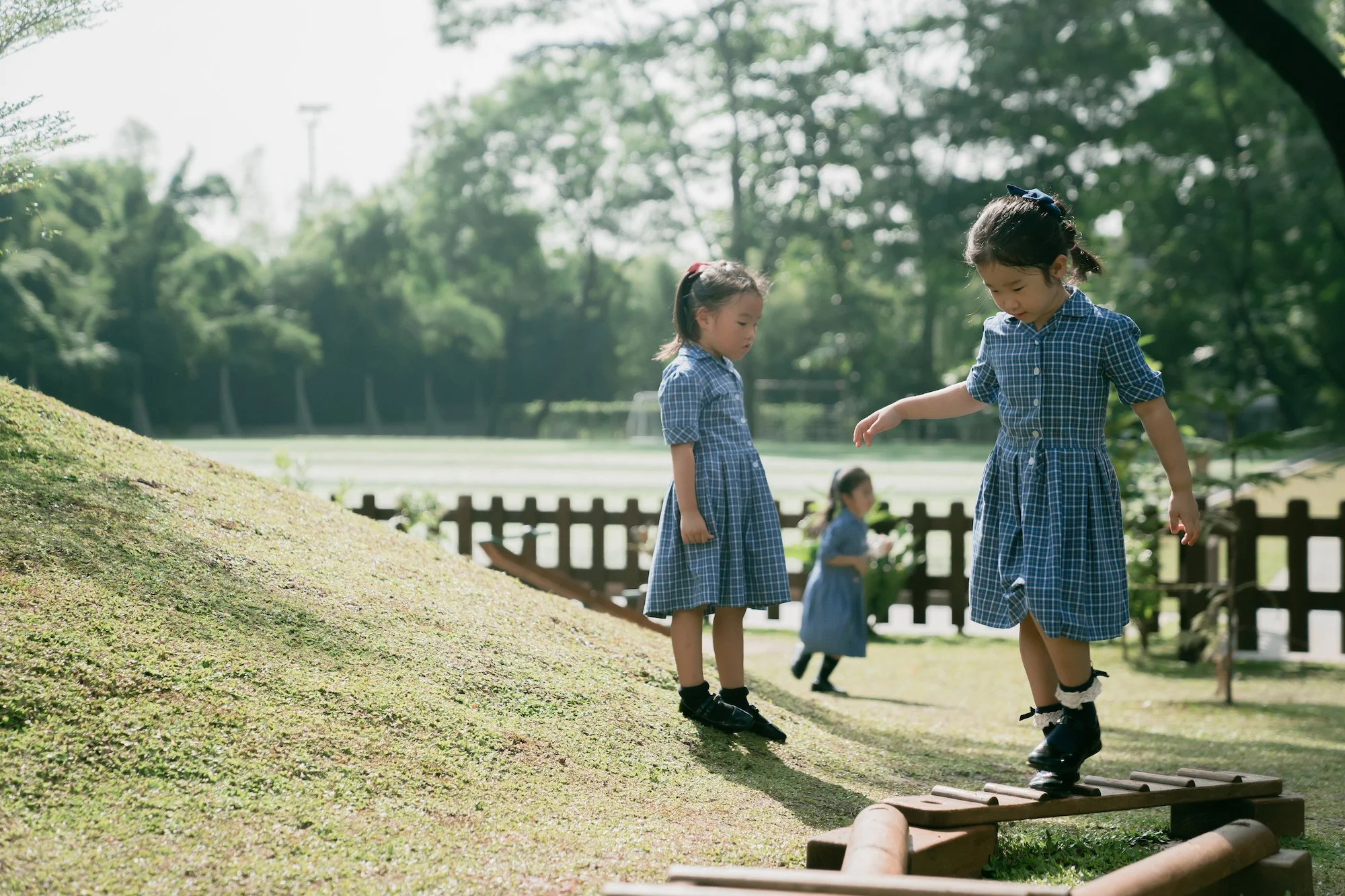 Two girls in gingham dresses playing on the ISJ campus lawn
